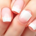 Close-up of durable French tip acrylic nails showing perfect white tips against a pink base