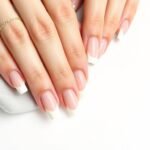 Elegant french tip acrylic nails almond shape with classic white tips on a neutral background
