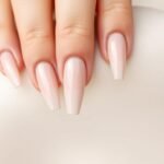 Elegant long almond acrylic nails in neutral tones with minimal gold accents