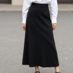 Woman wearing a black maxi skirt with a white button-up shirt and sandals
