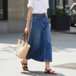 Woman wearing a long jean skirt with a simple white t-shirt and sandals for a casual summer day look