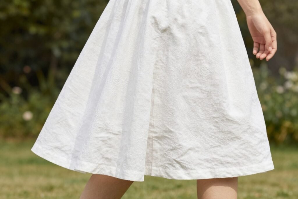 Woman wearing a textured white linen midi skirt showing the natural drape and texture of the fabric
