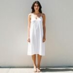 Woman wearing a white slip dress with minimal accessories in a 90s minimalist summer aesthetic