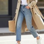 Woman wearing casual spring outfit with light wash jeans, white t-shirt, and beige trench coat
