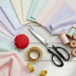 Colorful fabric pieces and sewing supplies arranged on a wooden table with scissors and measuring tape