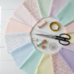 colorful fabric pieces and basic sewing supplies arranged on white workspace