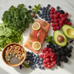 healthy foods for clear skin including salmon, avocado, berries, nuts and leafy greens arranged on marble surface